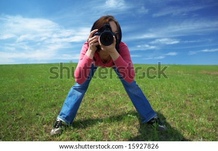 woman photographer in field under blue sky and clouds