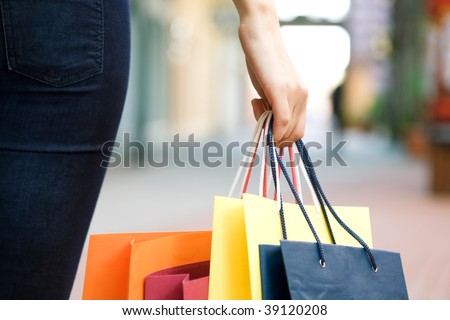 hand of young woman with multi-coloured bags with purchases