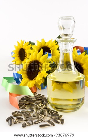 Sunflower seeds, a bottle of sunflower oil and sunflower with two colored ribbons on a white background into.