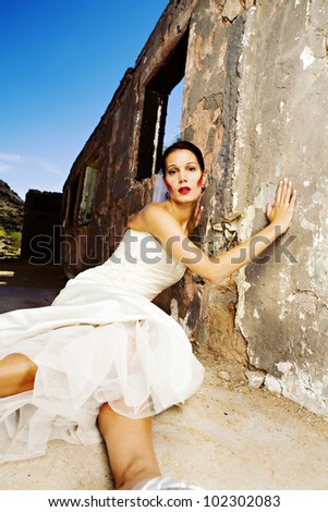 A beautiful bride sits  in front of an old grungy window