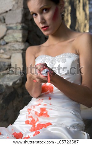 A beautiful bride trashes her wedding dress with red paint