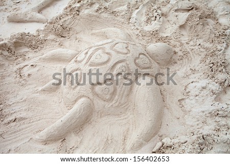 A turtle with hearts is sculpted in sand on a beautiful beach