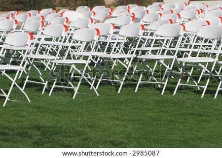 Folding Chairs set up on a green lawn for an event.