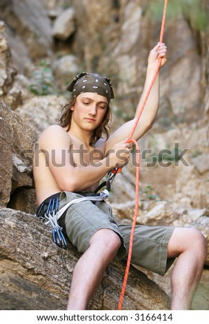 A teenager belays another climber using ropes. This secures the climber in case they fall