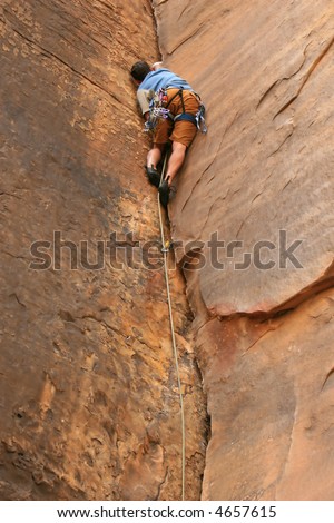 A rock climber works his way up a crack problem using traditional cams to anchor himself to the rock.