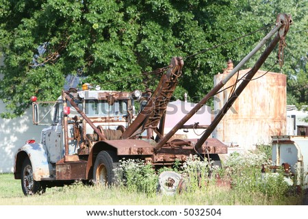 An old tow truck sits dormant and unused amongst over discarded equipment,trash,abandoned,discarded,scrap,scrapped,scrap heap,junk,junk yard