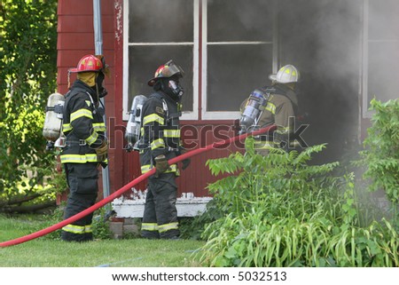 Three firemen work to out out a house fire in the midwest.