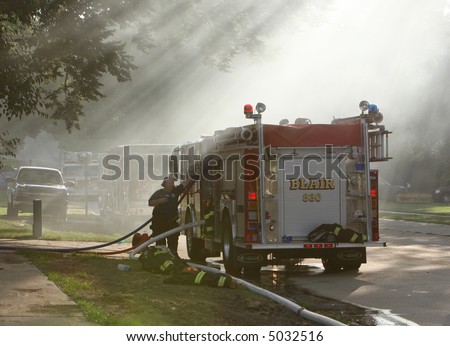 A fire truck used to pump water. They are putting out a small house fire.