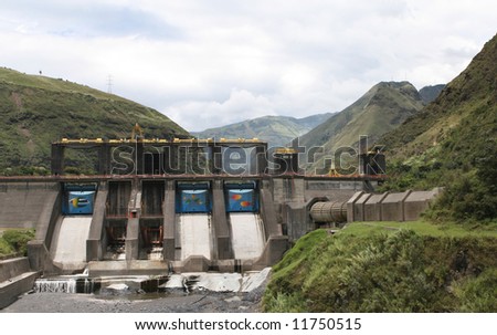 A large dam project produces power near Banos, Ecuador. Men can be see working on the dam in the second chute from the left