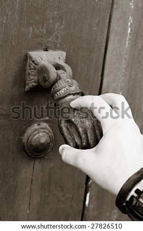 A female hand knocks an old-fashioned hand door knocker