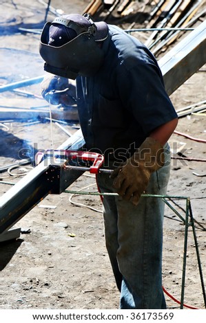 A worker welds two pieces of steel together using basic welding equipment