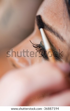 A young Indian woman has eye make-up applied at a salon