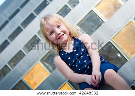 A smiling young girl sitting on steps with pink nail polish