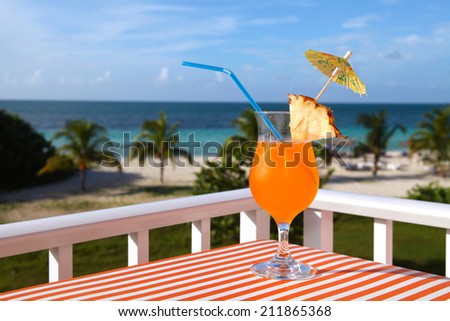 Close-up shot of the orange drink on the beach, sea and sky background