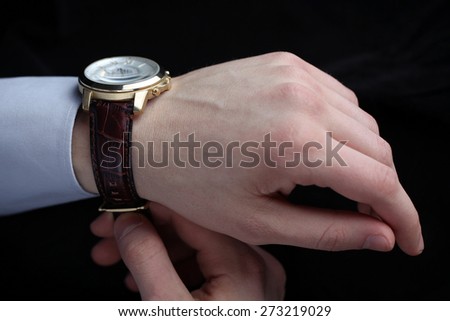 Man putting on wrist watch. Isoalted on black background, shallow focus.