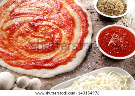 pizza preparation surrounded by ingredients