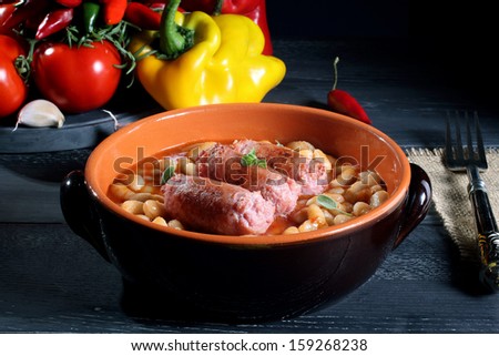sausages and beans in ceramic pan dark background