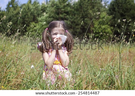 girl  sneezing because of pollen allergy in a garden in the spring