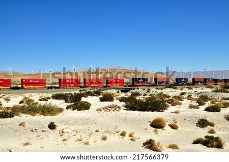 Palm Springs  - September 12, 2010 : Cargo train passing by the windmills in Palm Springs ,California, USA. A railroad car is a vehicle used for the carrying of cargo or passengers on a railway.