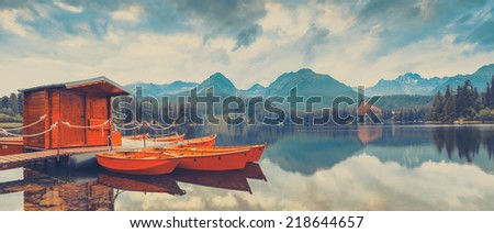 Reflection in water of mountain lake and boats. Mountain lake and empty boats in National Park High Tatra.