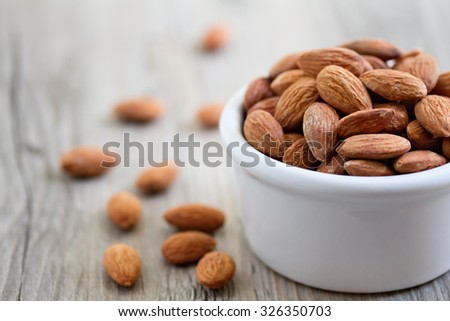 Bowl of almond nuts on rustic wooden table in natural light.