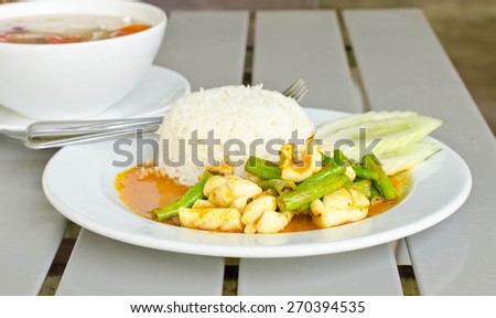 Squid curry with cooked rice in a white dish.