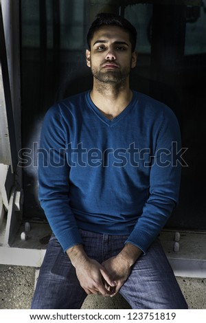 A young guy is sitting on a dark corner, sad, depressed and seriously thinking/Tough Time