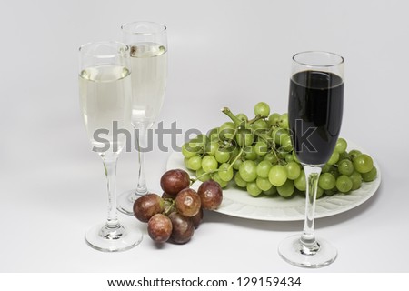 One plate of green grapes, a few of red grapes,  and two glasses of white wine and one glass of red wine