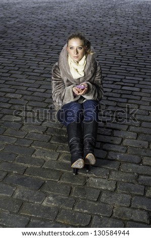 A girl holds a flower candle light and sits on the old brick ground/New light