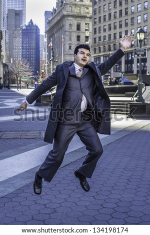 A young businessman is cheerfully jump on street