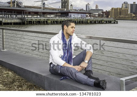 A young student is sitting by a river and into deeply thinking./Sitting Down and Thinking