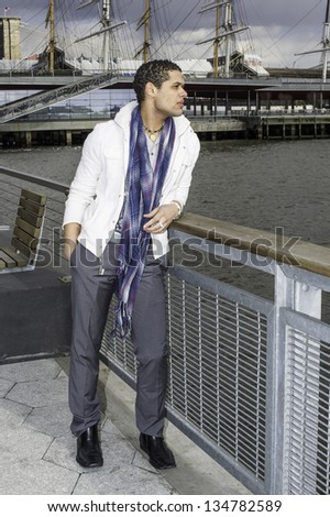 A young handsome guy is standing by the fence of a river, looking faraway./Waiting for You