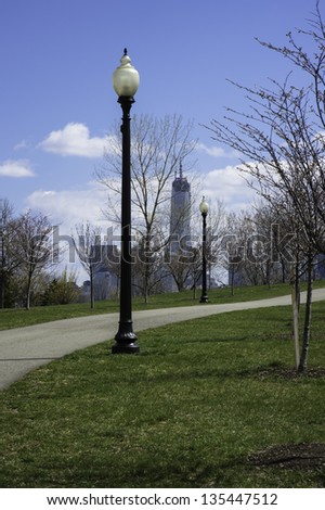 A small road in a green park. The background is the Freedom Tower./Road Lamps and Freedom Tower in Spring Season