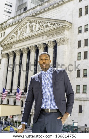 A young black businessman is standing in a business district and confidently looking forward/Portrait of Young Black Businessman