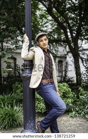 Leaning on a pole a young handsome guy is cheerfully looking at you./Happy Guy