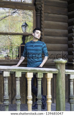A young handsome guy is standing by a window and thinking/Thinking Outside