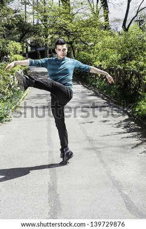 Stretching arms and legs, a young handsome guy is dancing in a park./Dancing in Park