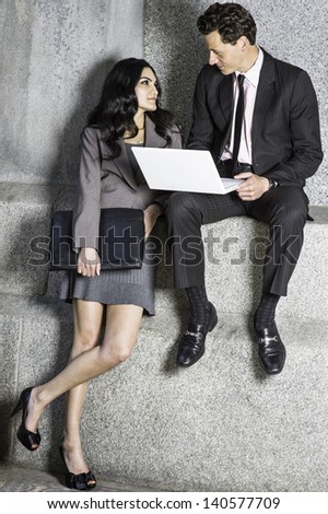 A young couple of businessman and businesswoman are working outside together and talking each other./Working Together