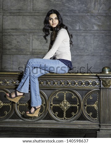 A young pretty woman is sitting on a metal railing and relaxing./Portrait of Pretty Woman