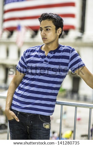Dressing in a fashionable pants and one hand putting in pocket, a young asian teenager is standing by railing and into deeply thinking/Thinking Outside