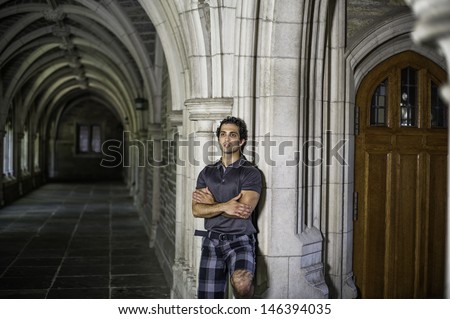 A young strong handsome guy is standing by a old fashion hall way, crossing arms and thinking / Portrait of Young Guy