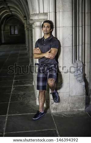A young strong handsome guy is standing by a old fashion hall way, crossing arms and thinking / Portrait of Young Guy