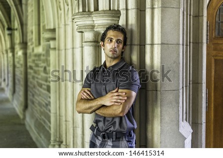 A young strong handsome guy is standing by a old fashion wall, crossing arms and thoughtfully looking away. / Portrait of Young Guy