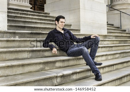 A young handsome guy is sitting on steps and relaxing. / Relaxing