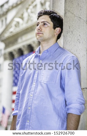 A young guy is sincerely looking forward. There are some American flags in the background. / Portrait of Young Guy