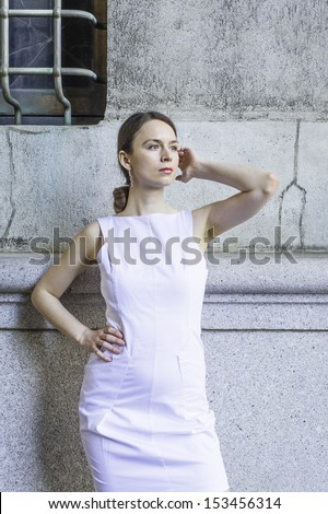 Dressing in a white sleeveless work clothes, a businesswoman is standing outside to take a break. / Take a Break