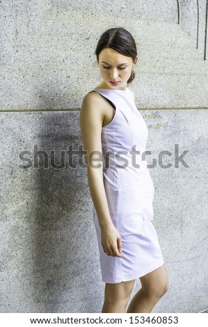 Dressing in white, a businesswoman is hanging her head and standing outside, very sad. / Unhappy Businesswoman