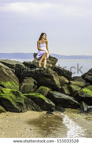 In the evening, a pretty girl is siting on rocks on the beach, waiting for you. / Bay Watch