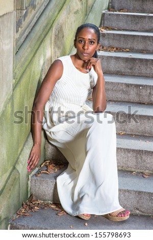 Dressing in a long white dress, sitting on steps, one arm supporting her head