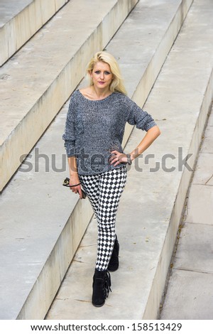 Dressing in a gray fashionable sweater, black and white pattern pants, black boots, holding a black leather purse, a young blonde girl is walking on steps. / City Girl